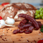 Kaminwurzen auf einem Holzbrett teils aufgeschnitten mit brot im hintergrund