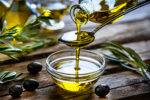 Bestes Olivenöl läuft über einen Löffel in eine Glasschale