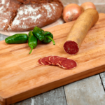 Schinken-Edelrohwurst von Almgold – luftgetrocknete Rohwurst aus Schinkenfleisch, rustikal angerichtet auf Holzbrett