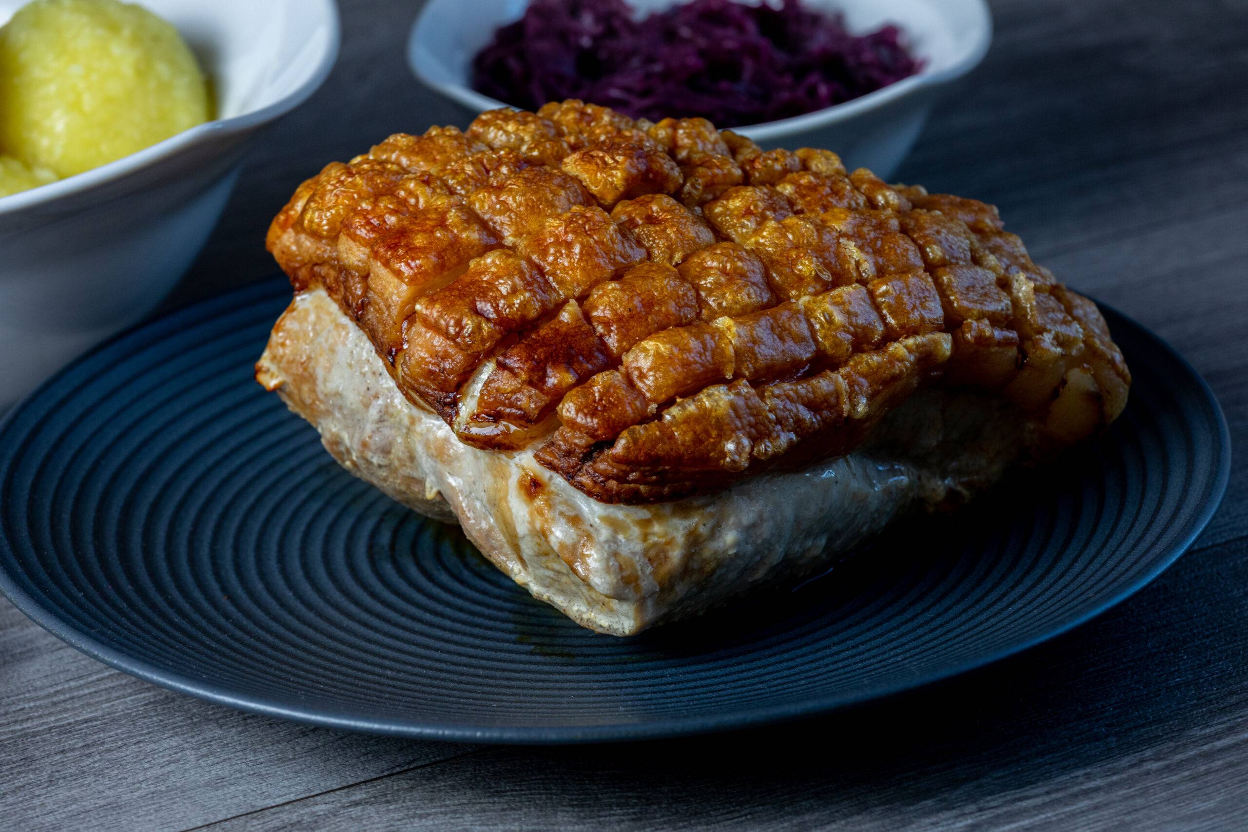 ganzer Schweinebraten mit knuspriger Kruste auf einem Teller