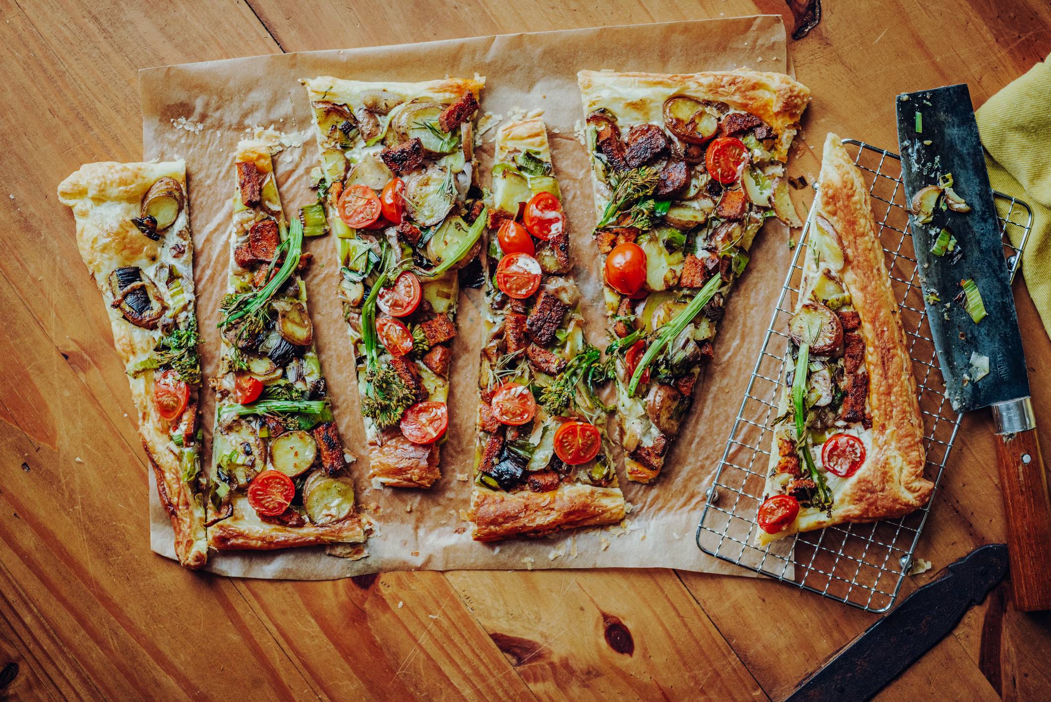 Vegetarischer Flammkuchen auf Backpapier und Holztisch präsentiert