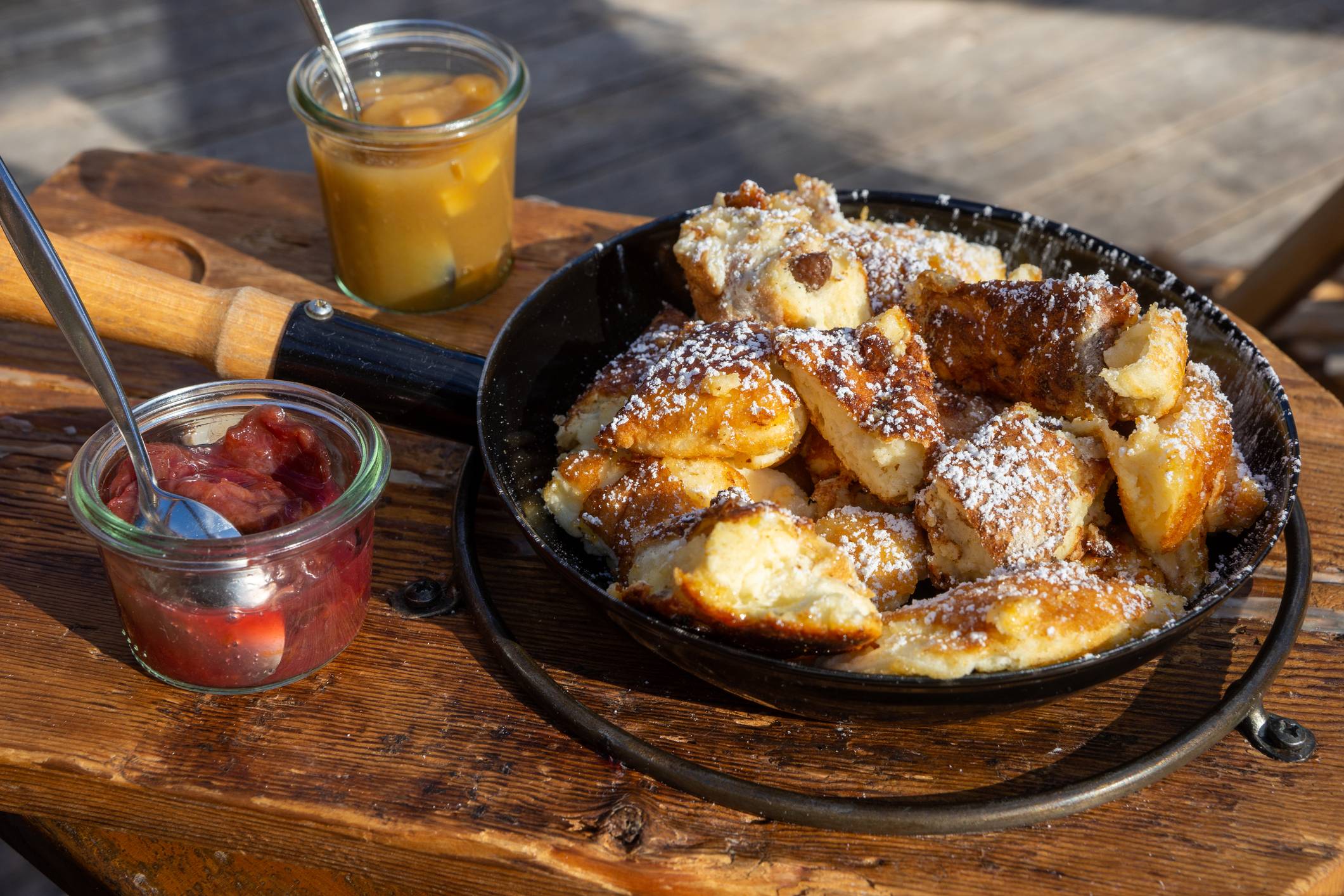 Original Wiener Kaiserschmarrn mit Puderzucker bestäubt mit Zwetschgenröster und Apfelkompott in einer Eisenpfanne serviert